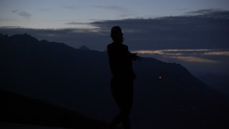 Slow-motion:-Beautiful-shot-of-silhouette-of-a-young-woman-standing-up-and-dancing-on-a-plattform-at-dusk