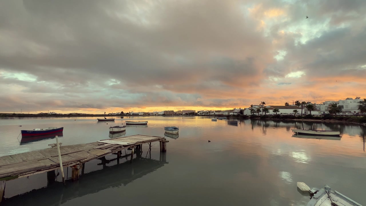 Small boats resting on the tranquil water during a vibrant sunset in barbate, andalusia, spain