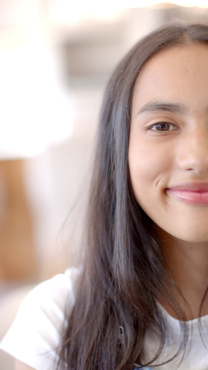 Vertical video: Smiling teenage girl with long hair enjoying time with friends indoors
