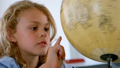 Cute-Caucasian-schoolgirl-studying-the-globe-in-a-classroom-at-school-4k