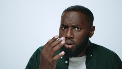 Portrait-of-attractive-african-american-man-checking-beard-look-in-studio.