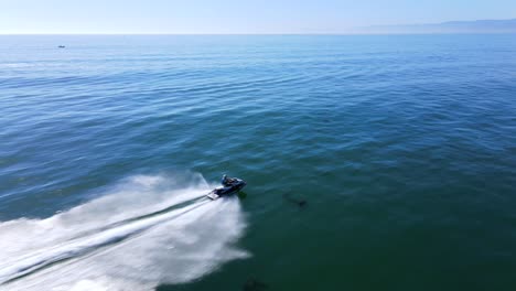 an excellent aerial shot of a man jet skiing on clear water