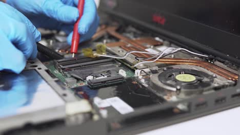 moving close up view of old laptop diagnostics by a professional technician with special equipment and protective gloves