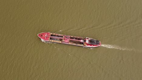 isolated red cargo ship sailing along amazon river