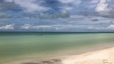 Panorámica-De-La-Cámara-A-Lo-Largo-De-La-Playa-Caribeña-Bordeada-De-Palmeras-Con-Gente-Disfrutando-Del-Agua-Clara