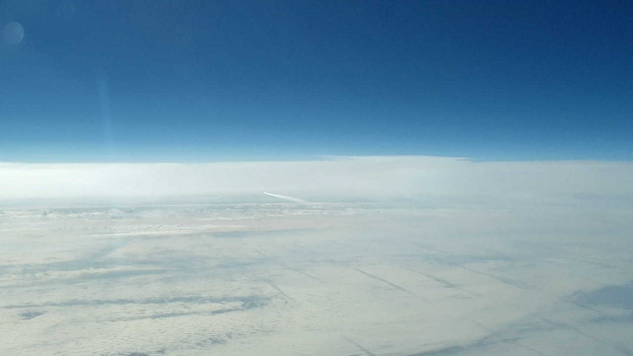 vista increíble desde la cabina de un avión que vuela alto por encima de las nubes dejando un largo rastro de aire de vapor de condensación blanco en el cielo azul