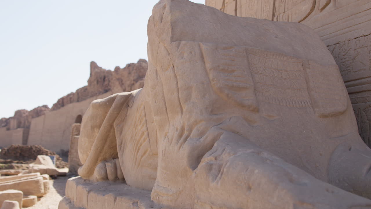 Ancient stone sculpture with inscriptions in Dendera, Egypt, against a clear sky