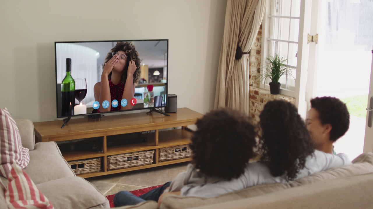 Famiglia afroamericana che fa una videochiamata in TV mentre è seduta sul divano a casa