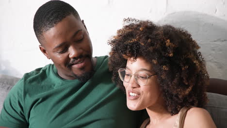 smiling diverse friends sitting together on couch, enjoying relaxed conversation at home