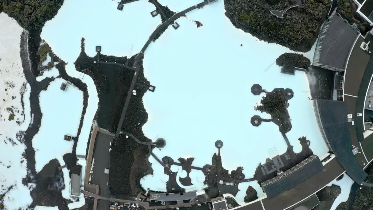 Blue Lagoon hot spring in Iceland, Open-air nature swimming pool with milky blue waters surrounded with volcanic landscapes, Overhead aerial view