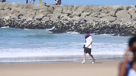 people are walking on sandy beach near the sea waves crushing to coastline shores, leisure and free-time concept of vacations and traveling concept