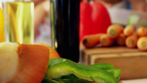 Grandmother-assisting-granddaughter-to-chop-vegetables-in-kitchen-4k