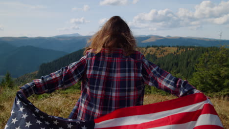 アメリカ国旗を持って山をハイキングしている女性