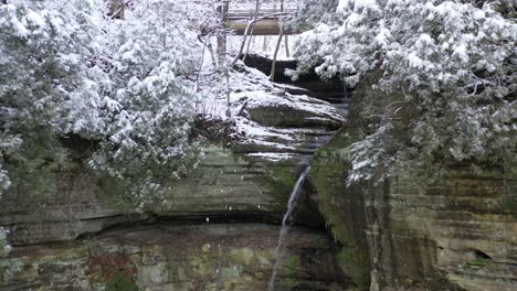 niveles de cascada, bosque cubierto de nieve y pared de montaña, ascenso aéreo