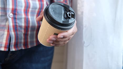 person holding a disposable coffee cup