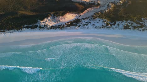 waves on white sand beach at sunrise