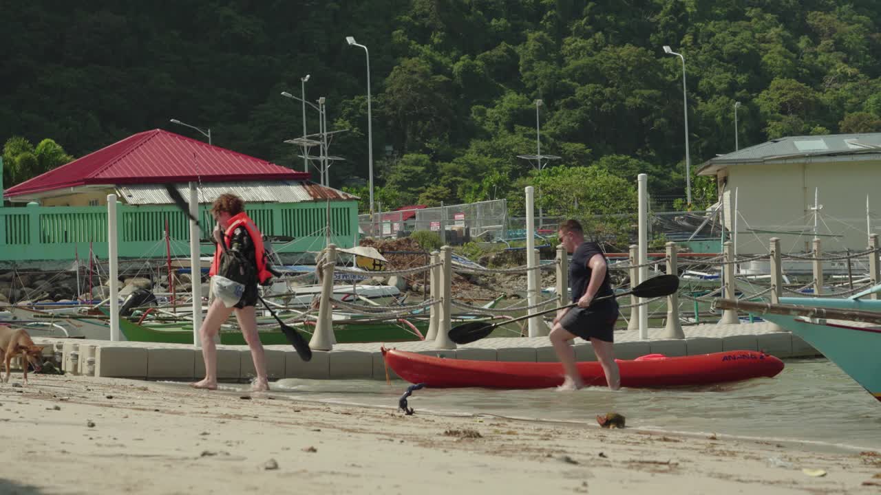 Tourist Pushing The Kayak Boat Onto The Shore In The Tropical Island in El Nido, Philippines - Perfect For Summer Activities - Wide Shot