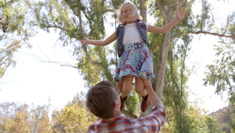 Papá-Sosteniendo-A-Su-Hija-Pequeña-En-El-Aire-En-Un-Parque