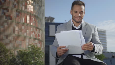 Businessman-looking-at-papers-on-street.-Manager-celebrating-success-outside