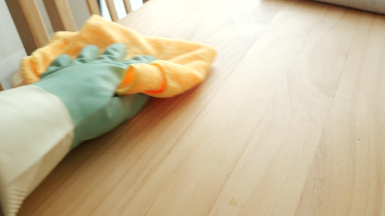 Cleaning a table with a rubber glove and a rag