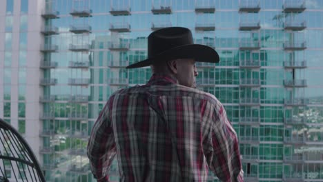 black man with black cowboy hat looking over balcony