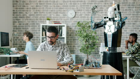 Robot in office, programmers and engineers working on project