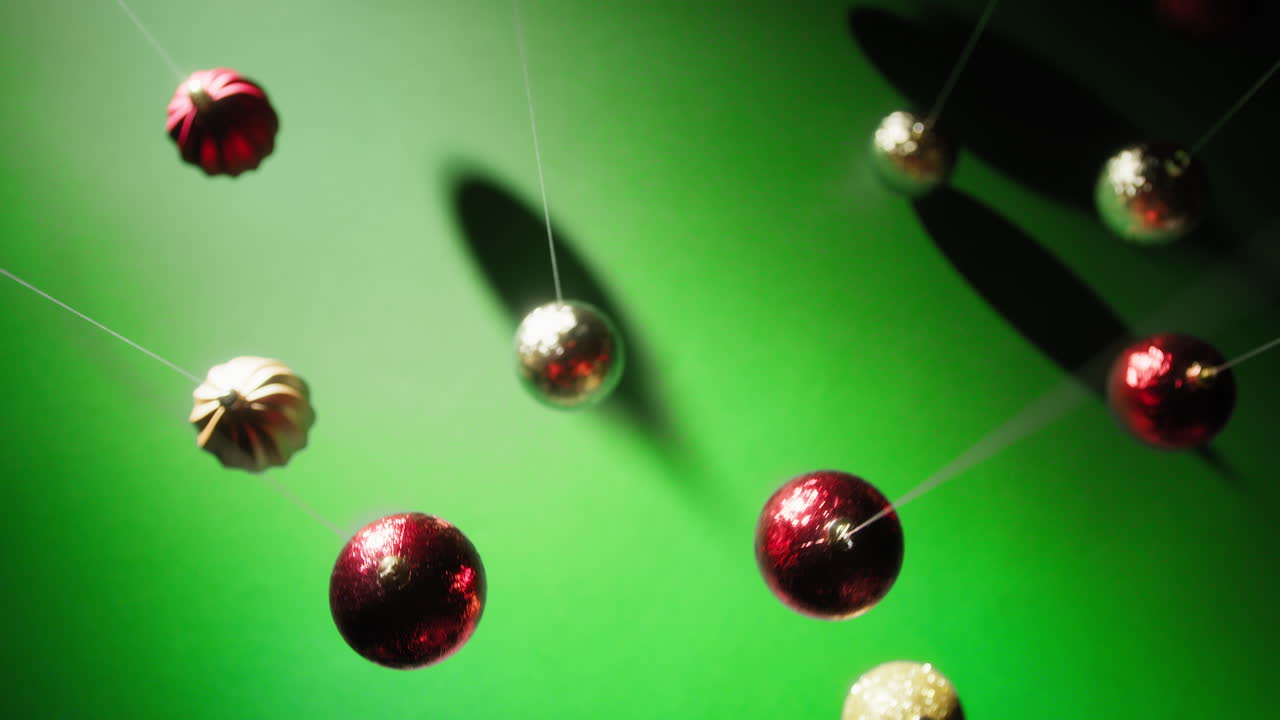Swinging Colorful Christmas Balls in Front of a Green Background
