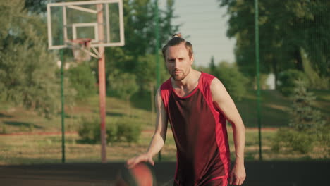 Ein-Konzentrierter,-Gutaussehender-Basketballspieler,-Der-An-Einem-Sonnigen-Tag-Auf-Einem-Basketballplatz-Im-Freien-Dribbelt