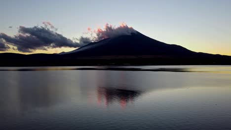 mount fuji silhouette at dusk with clouds, reflecting in calm lake waters, tranquil and serene scene