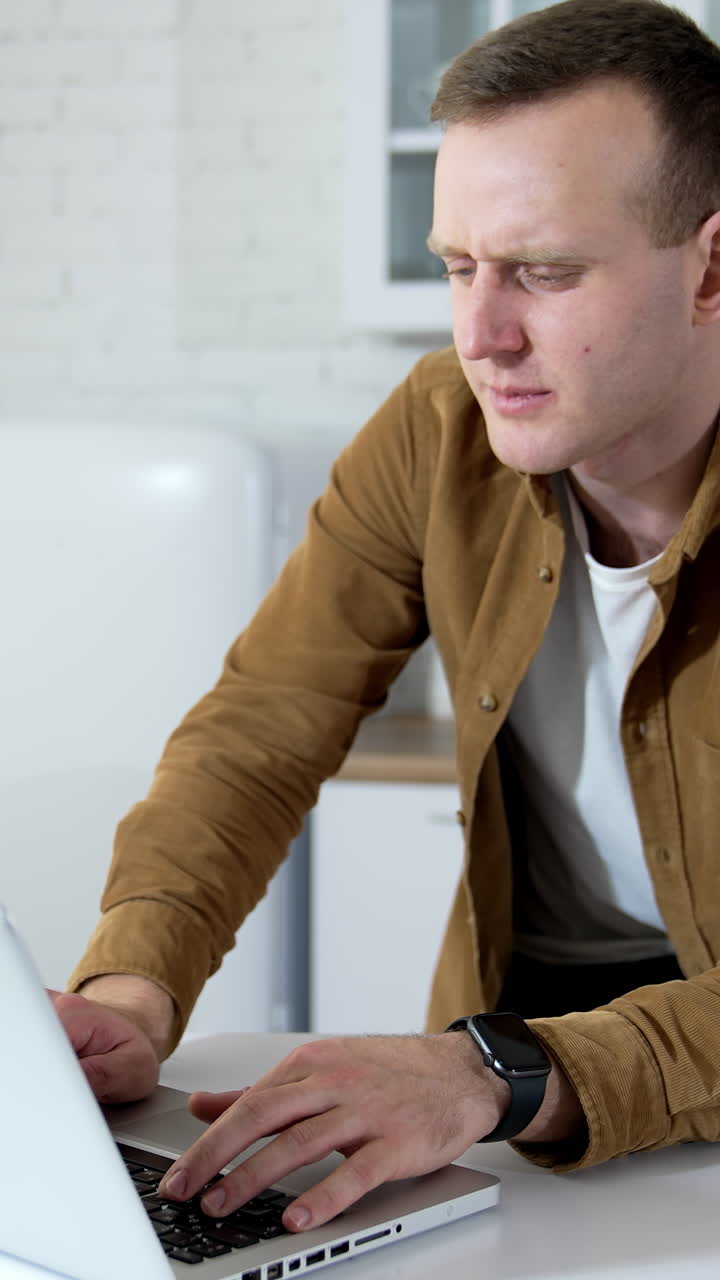 Young man speaking online. Freelancer male working with clients in front of a laptop. Student having a video call while sitting at home. Distant job. Vertical video