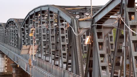 lateral pan revealing the intricate steel framework of the iron bridge between piacenza and cremona, glowing in soft golden hour light