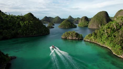 small boat drives through in raja ampat indonesia, in between tropical islands, turquoise waters, and coral reefs