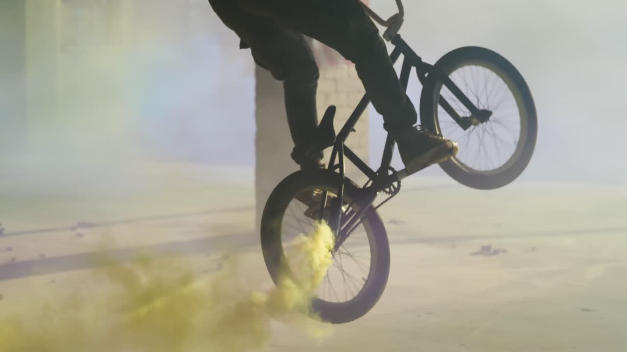 BMX rider in an empty warehouse using smoke grenade