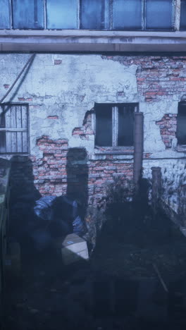 a decaying brick wall with windows and trash bags in front of it