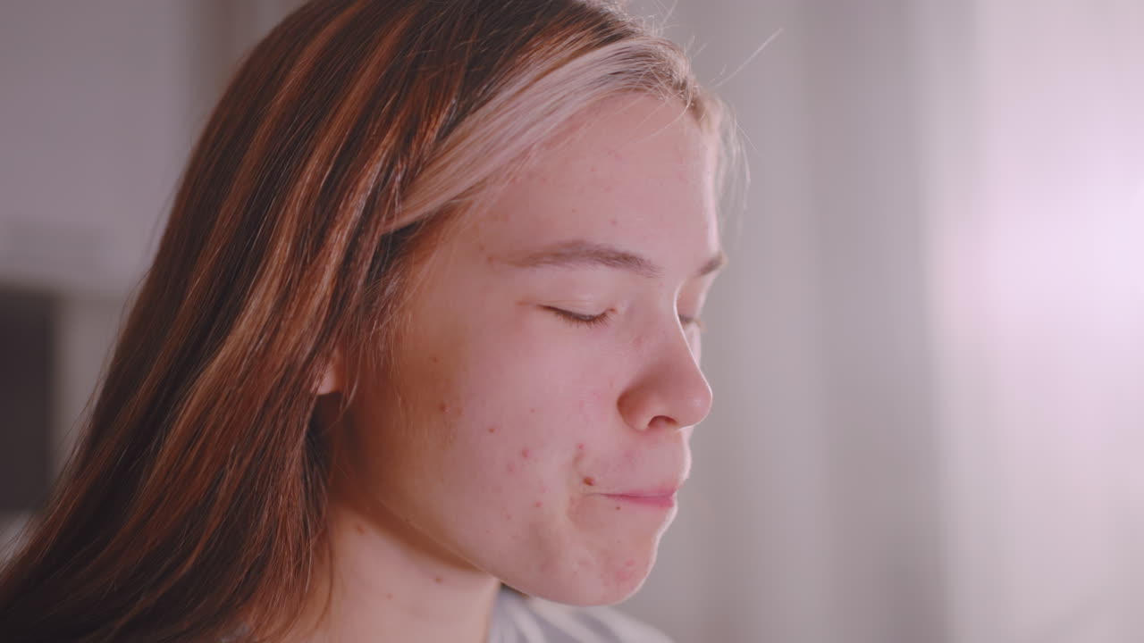 Close up of woman sipping tea from glass cup with eyes closed in relaxed enjoyment, sunlight softly illuminating face, capturing warm indoor atmosphere of peaceful morning beverage