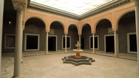 Courtyard-of-an-Arabic-mosque-in-Sbeitla-with-ornate-arches-and-a-fountain,-daylight