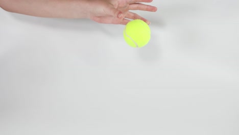 hand dropping a tennis ball onto surface