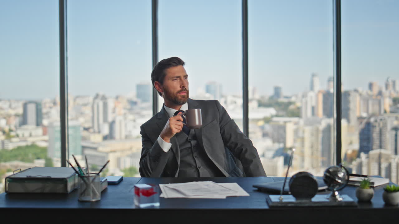 Dipendente pensieroso che beve caffè in un ufficio panoramico. Uomo d'affari adulto che si riposa.