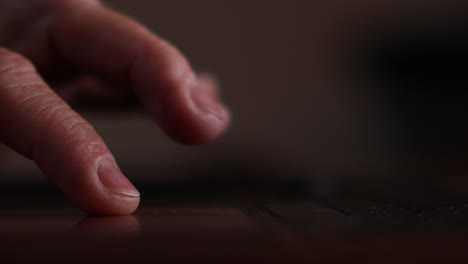 Close-up-of-man's-finger-scrolling-on-track-pad-of-laptop-backlit-by-the-screen