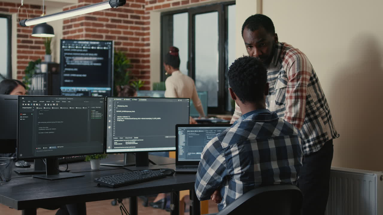 Software developer writing code on laptop and computer keyboard looking at multiple screens