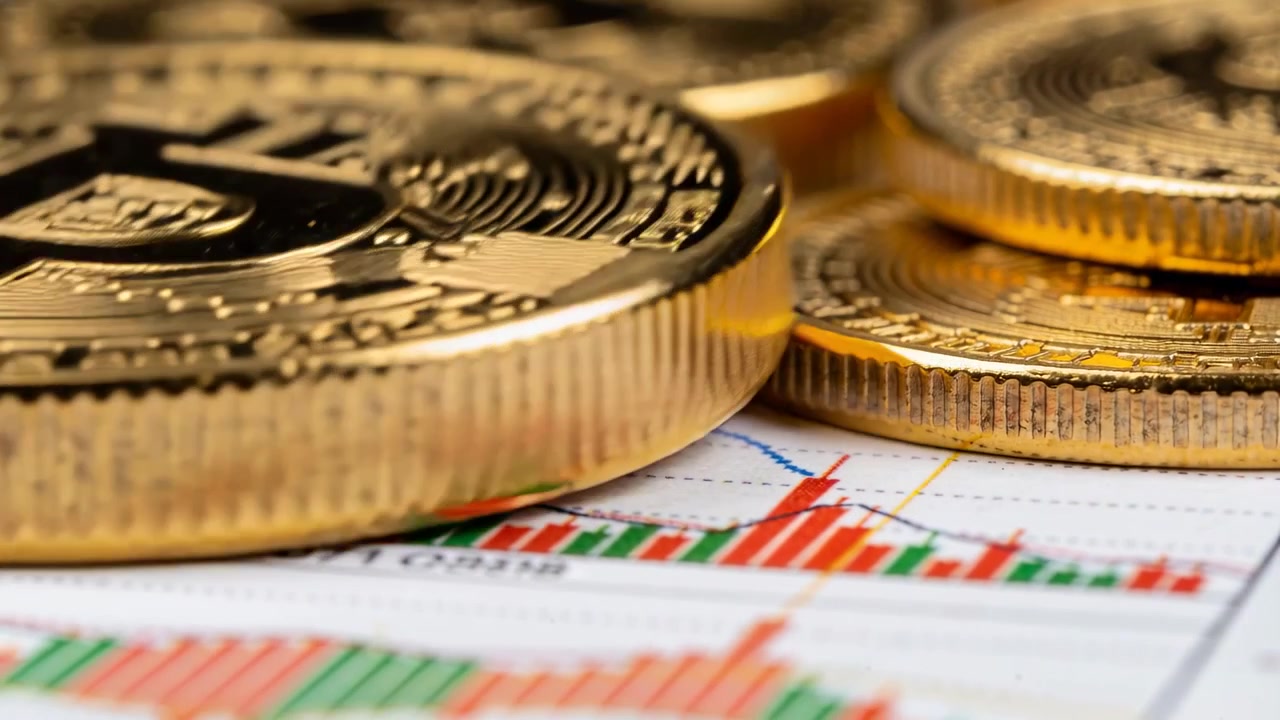 Telecamera che si allontana, mettendo a fuoco token Bitcoin d'oro impilati su un grafico finanziario, rivelando una tendenza.
