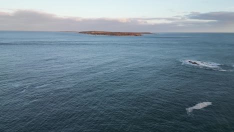 A-fly-over-of-Mira-Bay-from-Scatarie-Island,-Flying-towards-a-small-town-over-looking-the-ocean