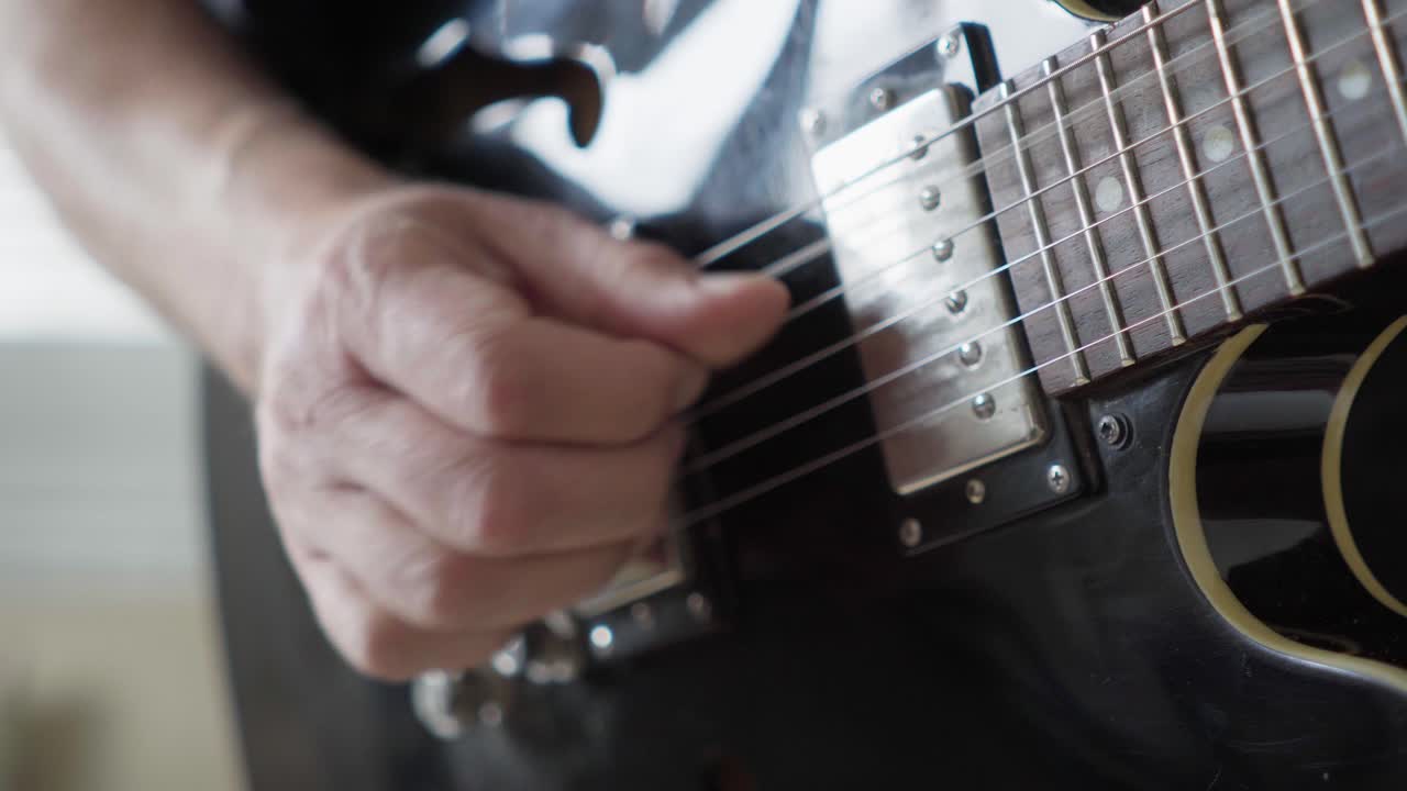 Close-up of a guitarist's right hand playing fingerstyle on an electric 335-style guitar