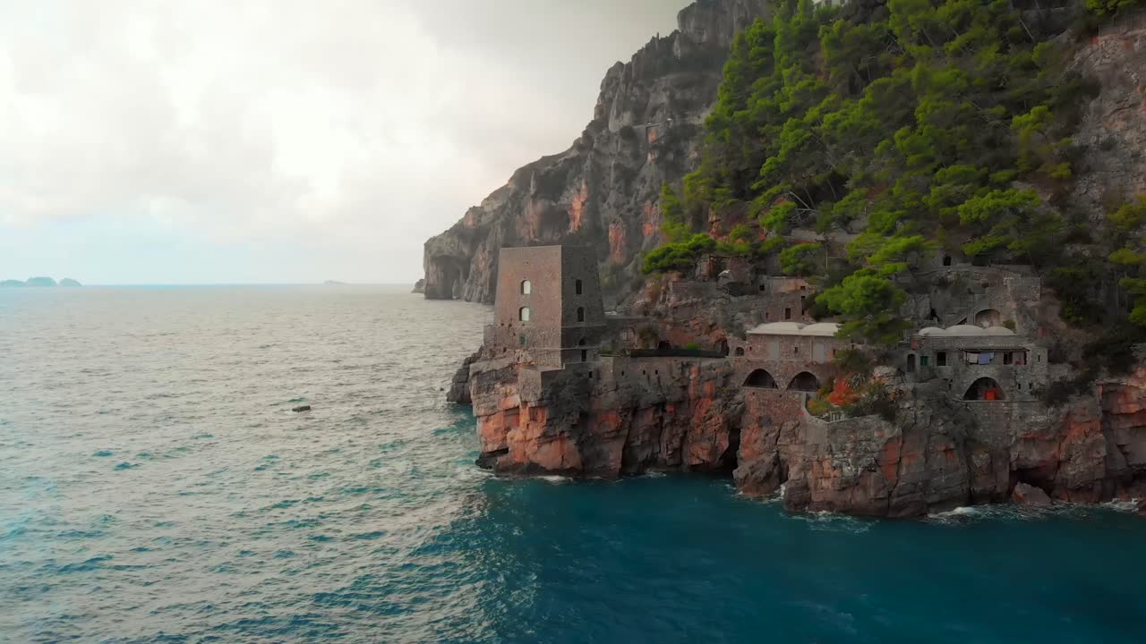 Captivating aerial view of stormy Positano, Italy, showcasing a majestic castle perched on the cliffs, offering a unique Airbnb experience