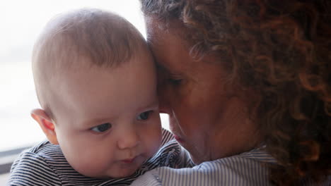 baby grandson looking over grandmothers shoulder as she cuddles him