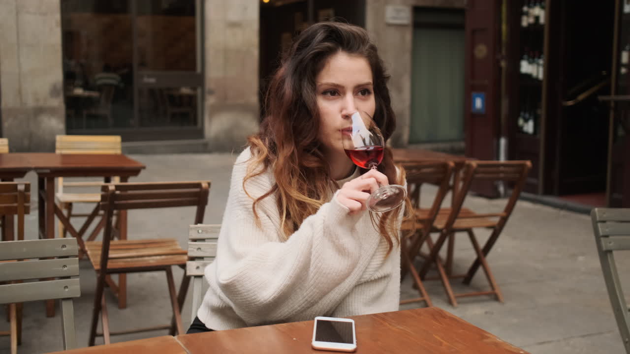 joven sonriendo a la cámara y bebiendo un vaso de vino tinto