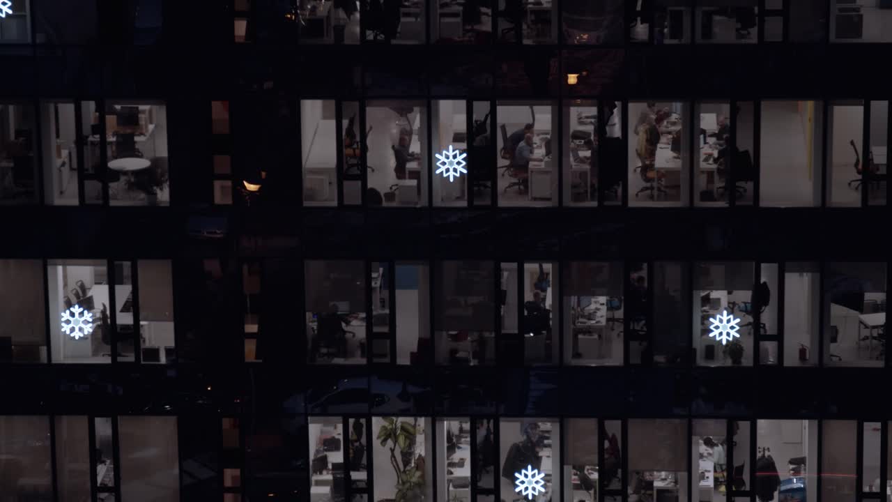 Corporate building offices packed by a lot of active, hard working people shot through windows in the night