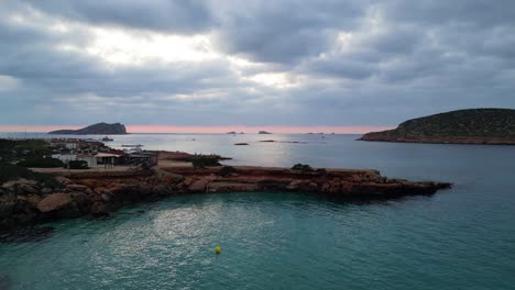 Perfecto-Aéreo-Vista-Superior-Vuelo-Yoga-Chica-Posición-árbol-Atardecer-Acantilado-Playa-Isla-Ibiza-España-Volar-Drone-Inverso