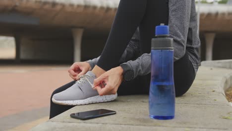 mujer en ropa deportiva atando sus cordones de zapatos