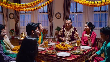 family members wearing traditional attire sitting around decorated table, sharing delicious meal while engaging in animated conversation and laughter, radiating warmth and cultural connection